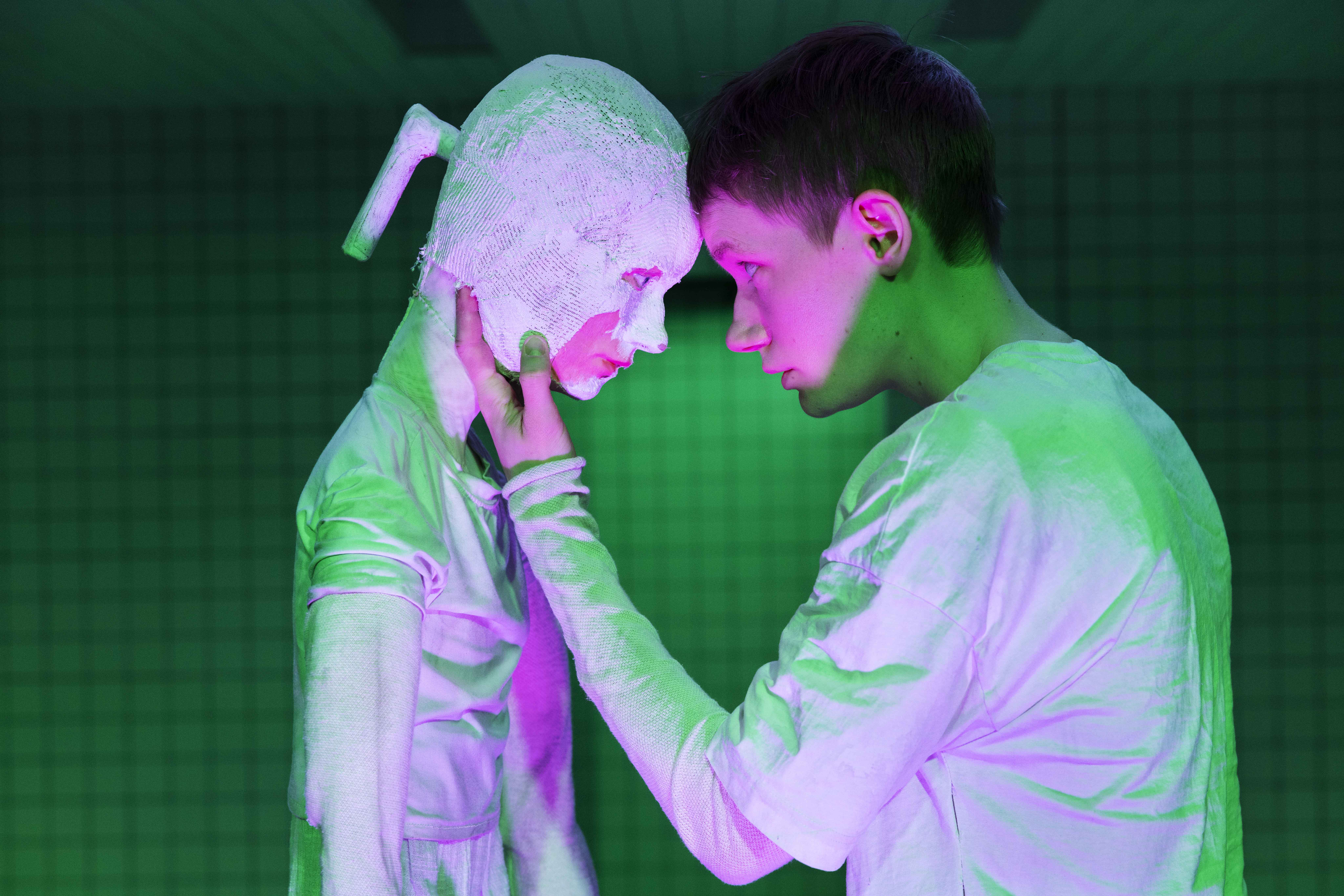 To skuespillere står på en scene i grøn belysning